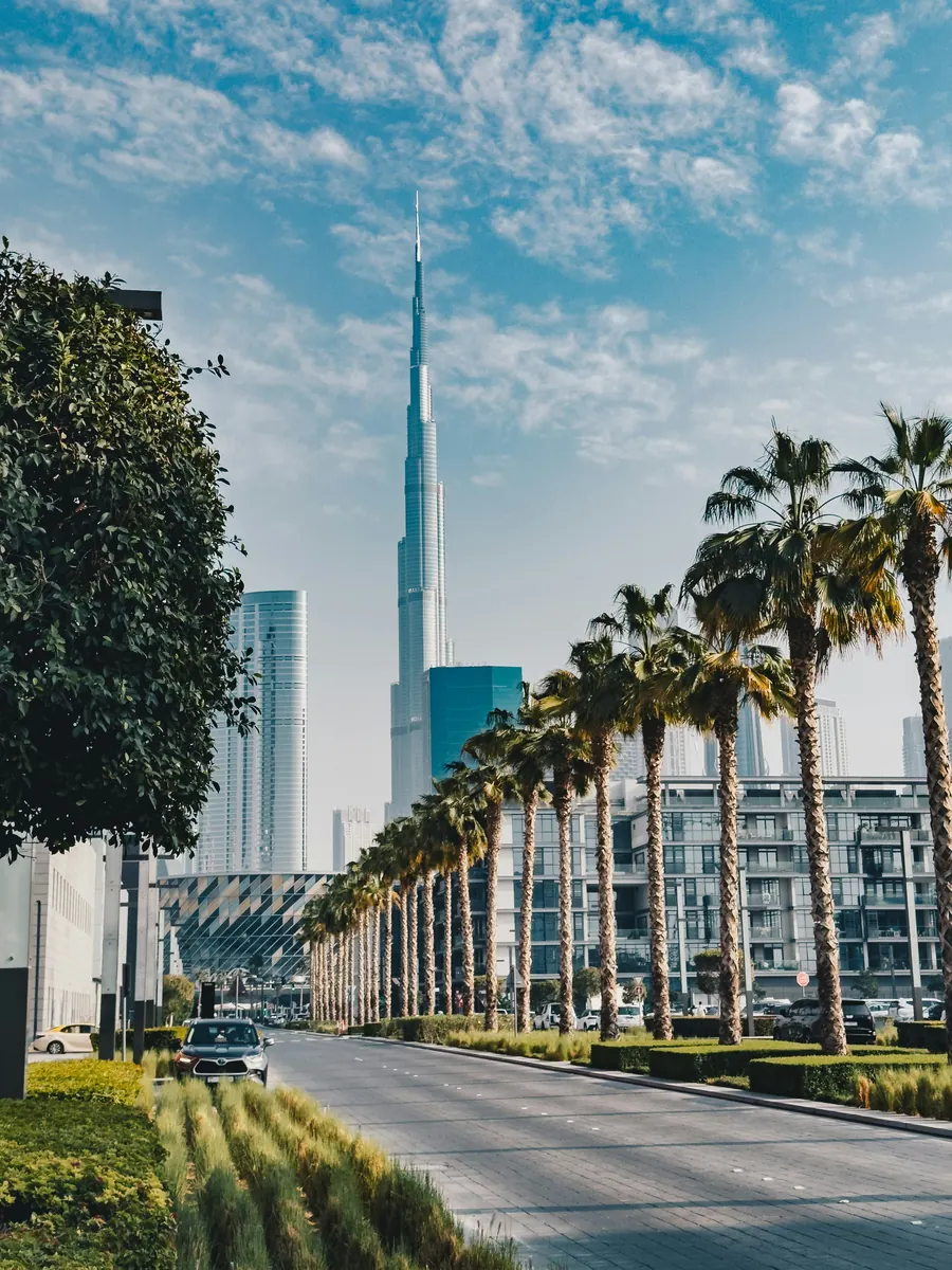 A palm-lined Dubai boulevard leading toward the Burj Khalifa